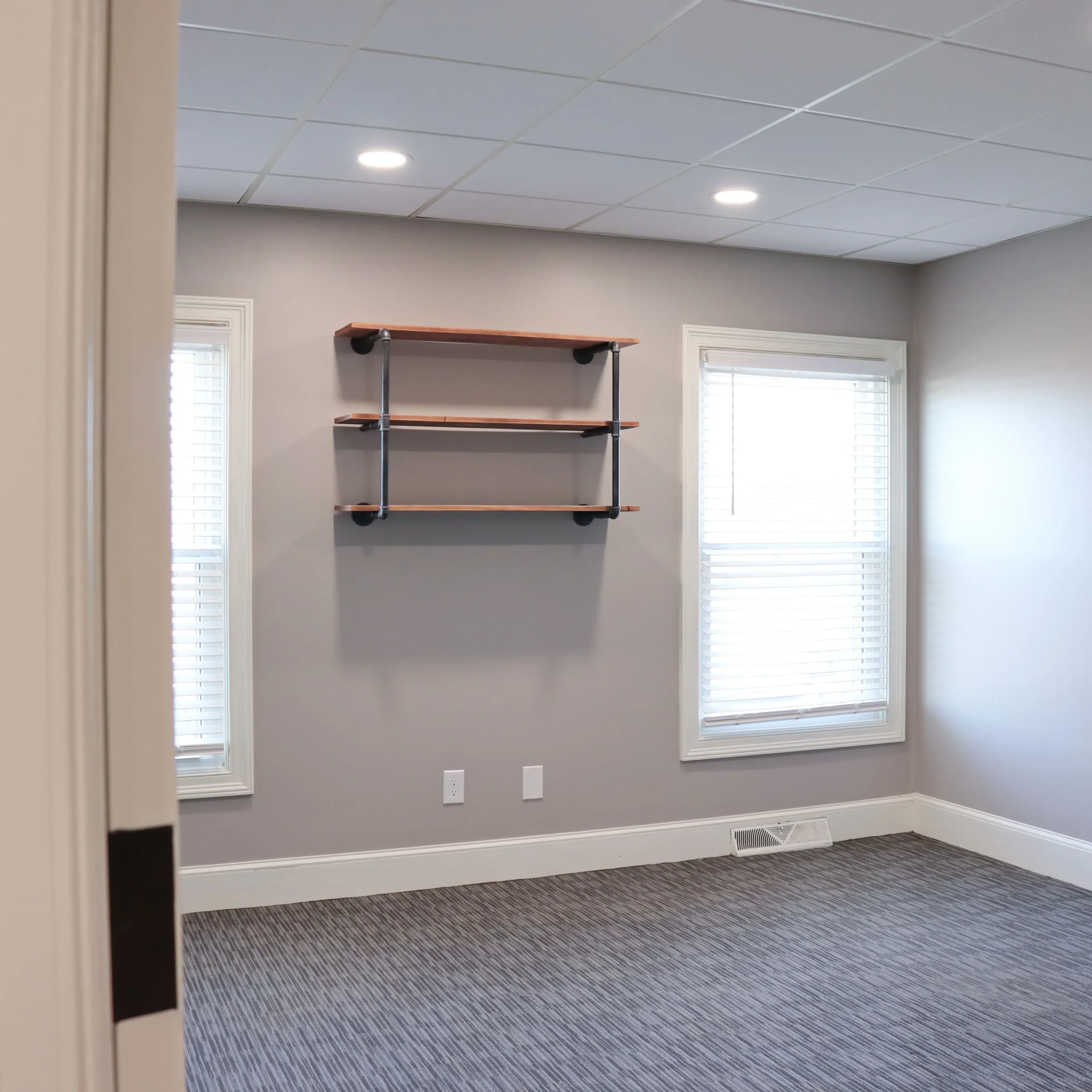 Empty office space with two windows and shelves available for rent
